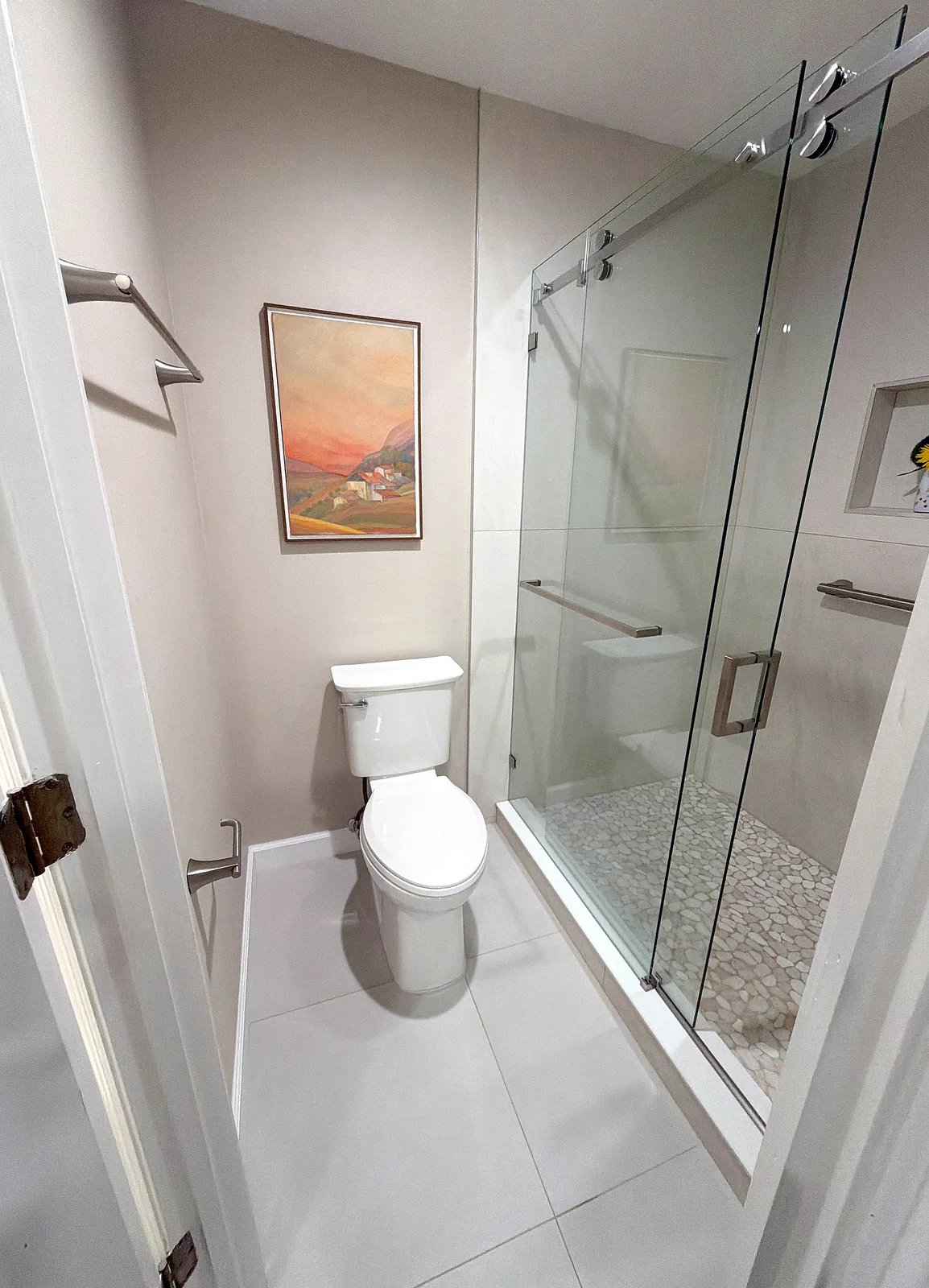Bathroom remodel with a frameless sliding glass shower enclosure, large-format tile walls and a pebble mosaic shower floor - After