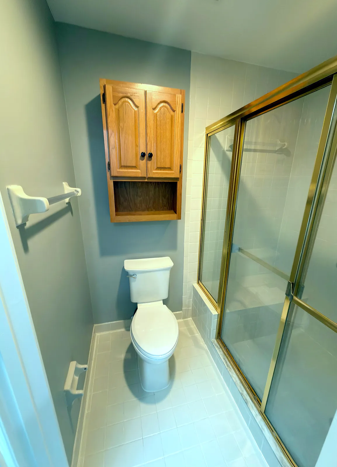 Bathroom remodel with a frameless sliding glass shower enclosure, large-format tile walls and a pebble mosaic shower floor - Before
