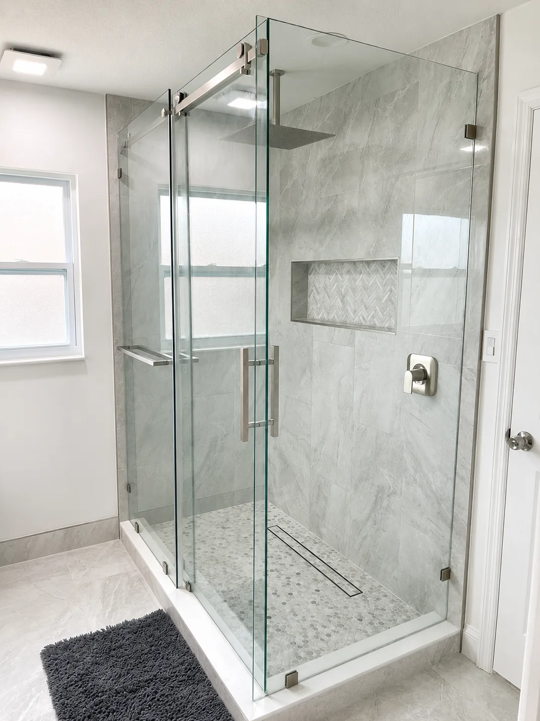 Walk-in shower with grey marble-look porcelain tile, a herringbone mosaic niche and a linear drain