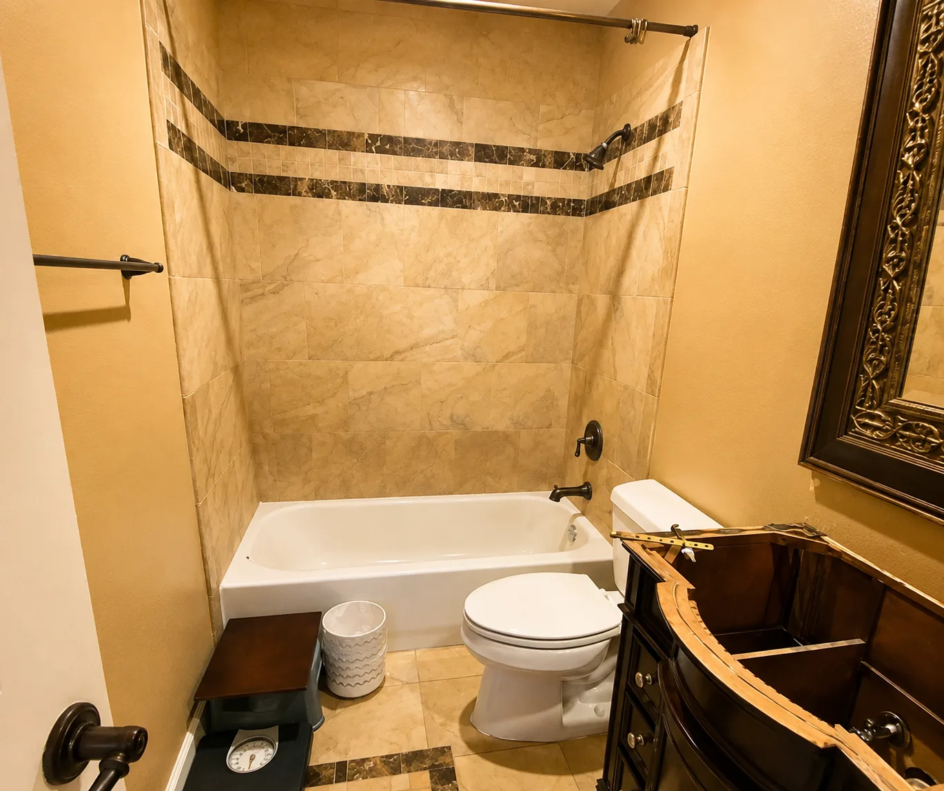 Bathroom remodel converting a dated tiled tub surround into a walk-in shower with black framed glass doors and a black vanity with quartz countertop - Before