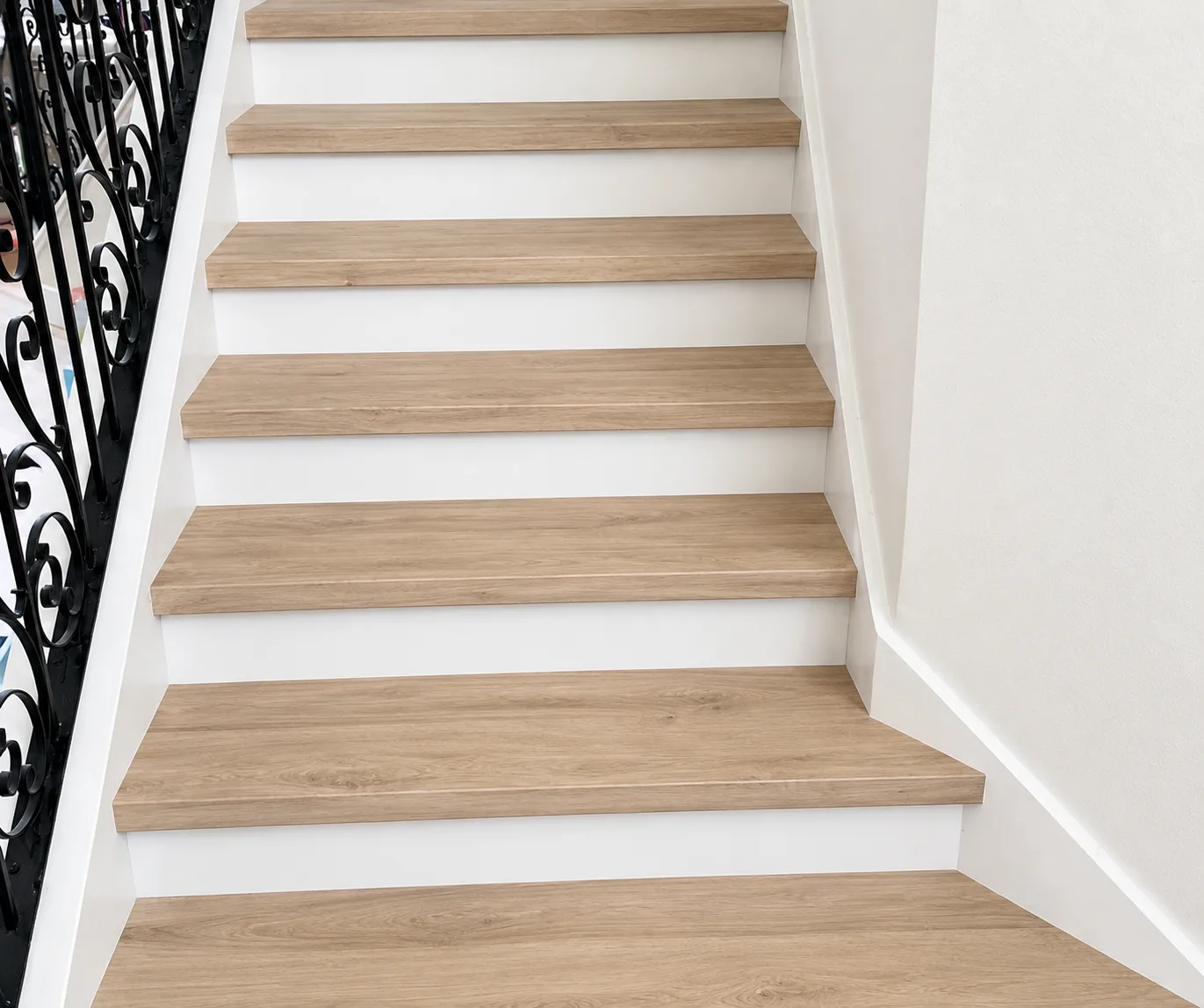 Staircase refinished from orange-toned oak treads to light oak luxury vinyl plank with white risers - After