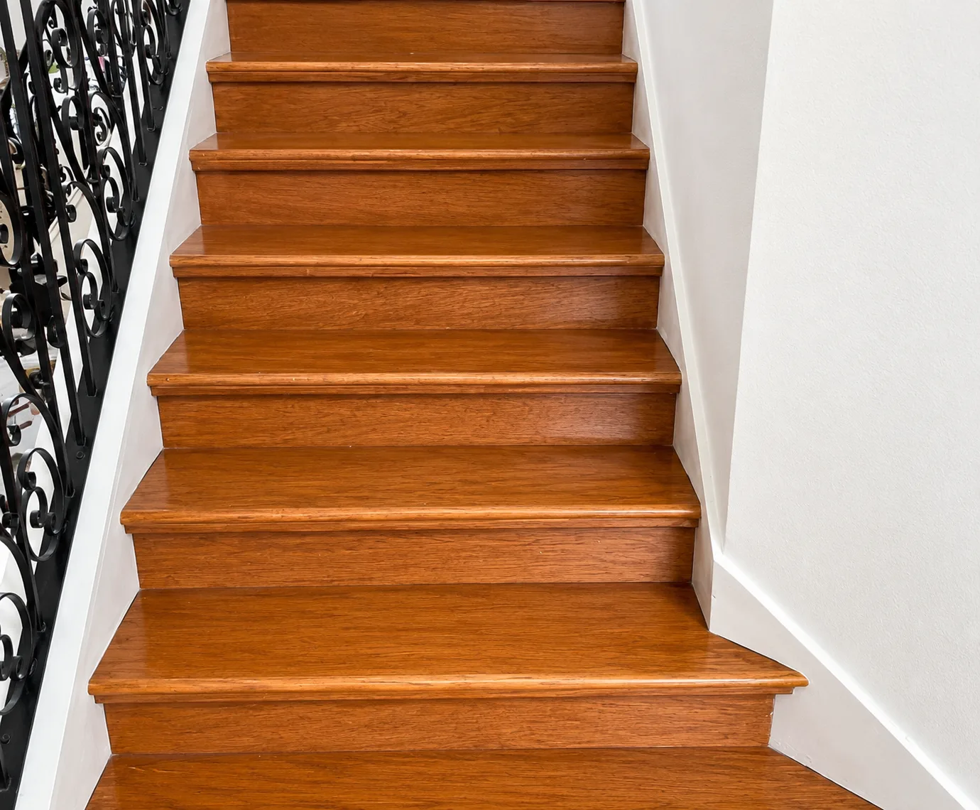 Staircase refinished from orange-toned oak treads to light oak luxury vinyl plank with white risers - Before