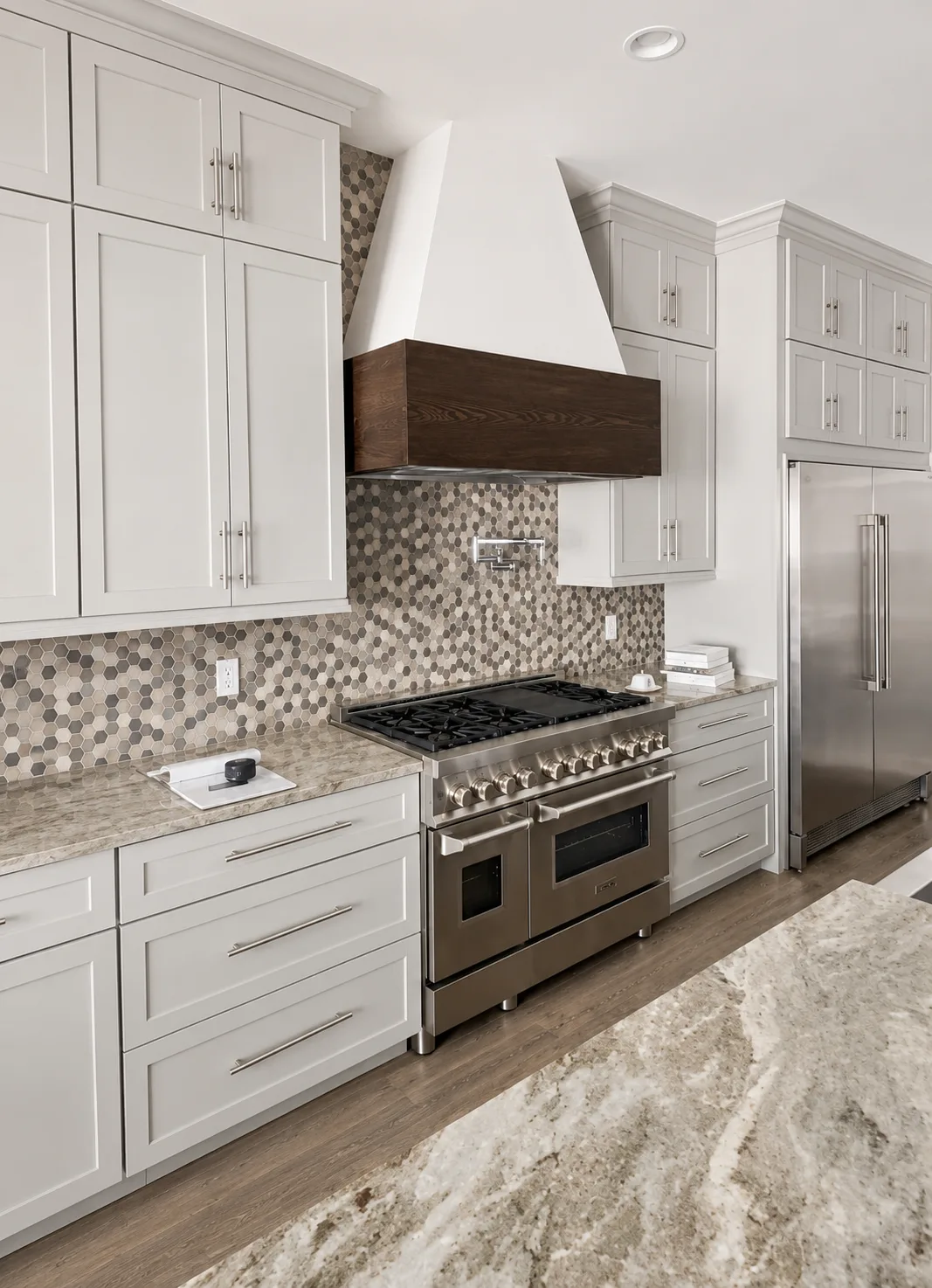 Kitchen remodel with white shaker cabinetry, brass hardware, a marble-look quartz waterfall island, full-height backsplash and custom range hood - Before