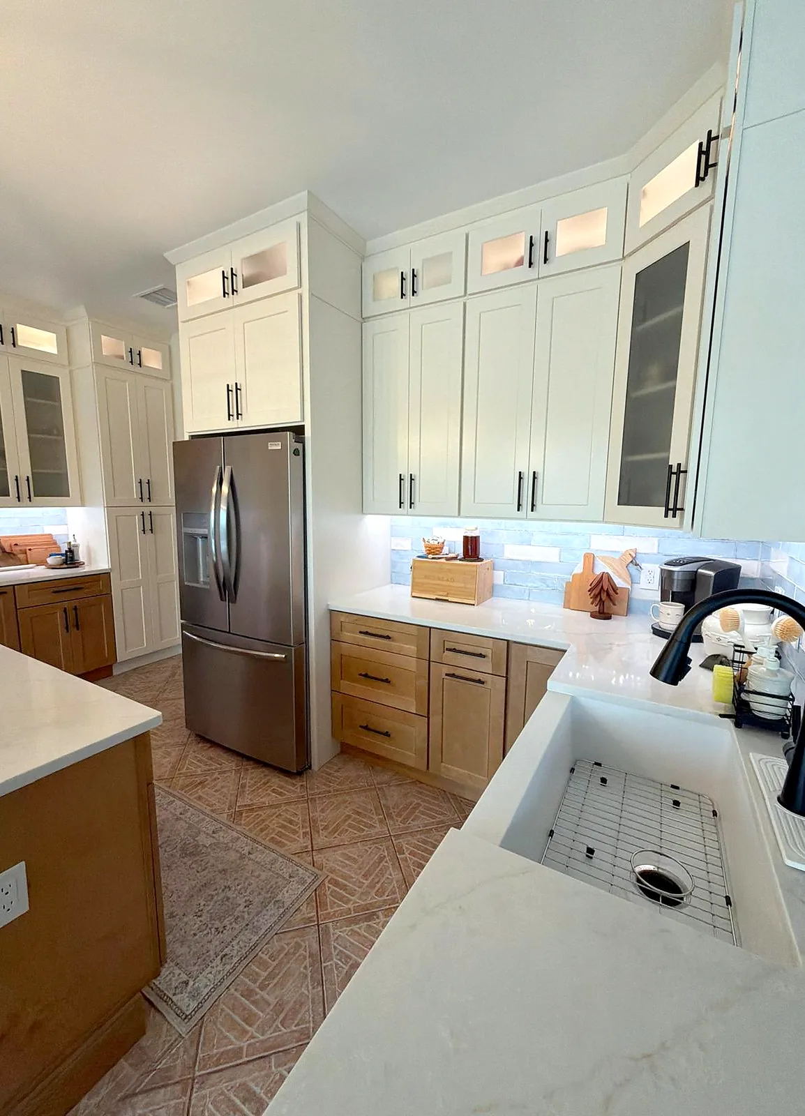 Kitchen remodel with cream shaker cabinetry, glass-front upper cabinets, quartz countertops, a farmhouse sink and a blue tile backsplash - After