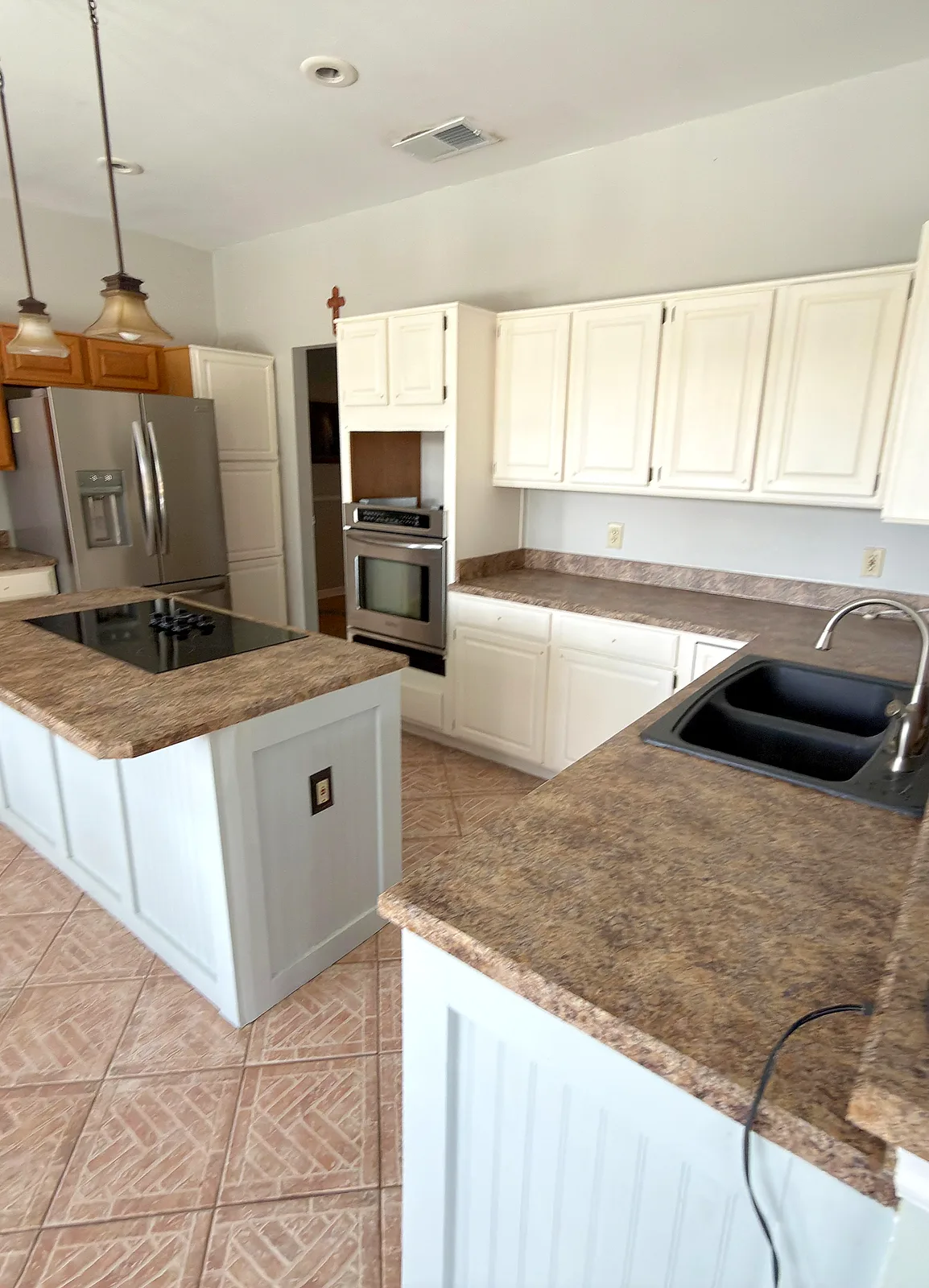 Kitchen remodel with cream shaker cabinetry, glass-front upper cabinets, quartz countertops, a farmhouse sink and a blue tile backsplash - Before