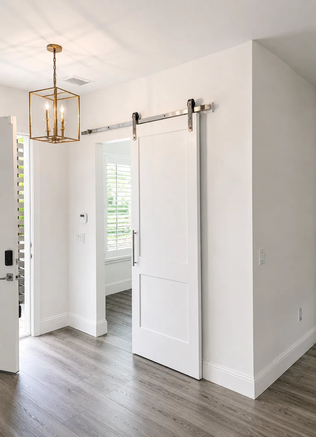 Interior remodel with a white barn door, brass lantern pendant and wood-look vinyl plank flooring